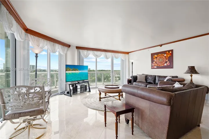 Living area featuring polished stone tile flooring, floor-to-ceiling glass walls, and crown molding