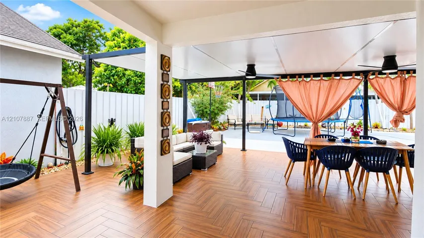 Covered patio featuring wood-finish flooring in a herringbone pattern, integrated ceiling fans, and a solid roof structure