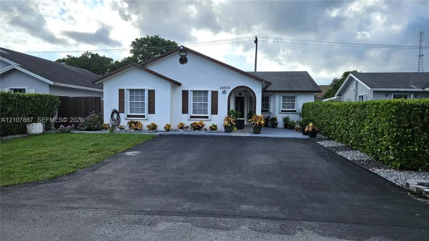 Single-story residence featuring a smooth stucco exterior, arched covered entryway, asphalt driveway, and shuttered windows