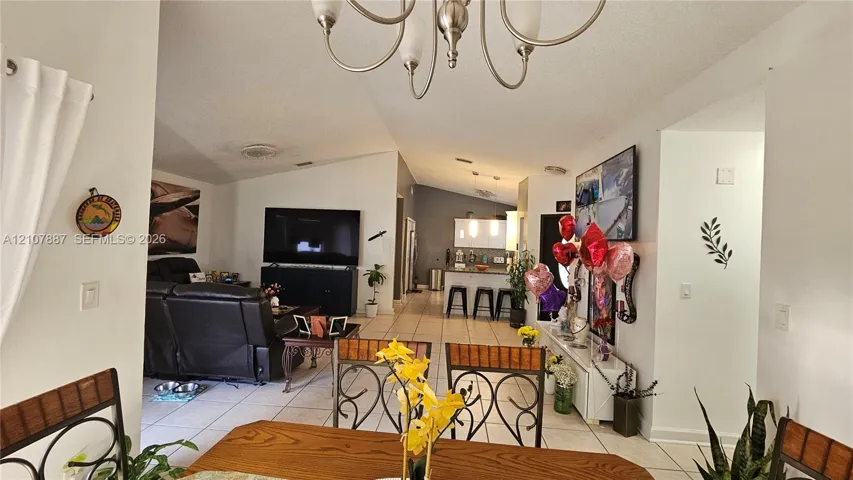 Vaulted ceilings, tile flooring, and a multi-arm chandelier featuring brushed metal finish