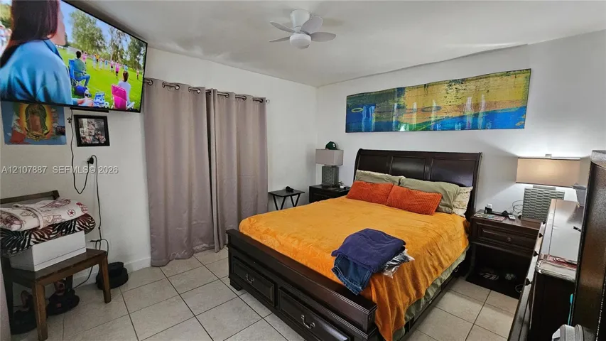 Neutral-toned tile flooring, ceiling fan, and window drapery