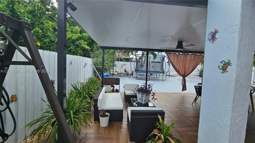 Covered outdoor patio featuring wood-finish tile flooring, a built-in ceiling fan, and privacy fencing