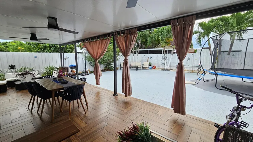 Covered patio featuring wood-finish flooring in a herringbone pattern, integrated ceiling fans, and a solid-surface concrete flooring extension