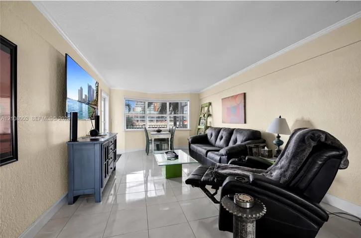 Living area featuring light-colored tile flooring, textured wall finishes, and a bay window