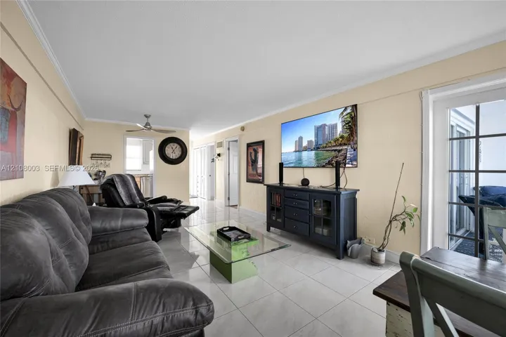 Living area featuring light-toned tile flooring, recessed ceiling lighting, a dedicated ceiling fan, and multi-pane glass door paneling