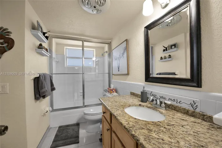Bathroom featuring a vanity with a stone-finish countertop, undermount oval sink, chrome dual-handle faucet, and built-in wood-finish cabinetry