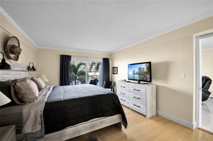 Light-filled room featuring wood-finish flooring, sliding glass doors, and dual wall-mounted light fixtures