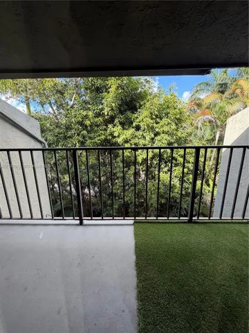 Covered balcony featuring concrete flooring, artificial turf, and metal railing