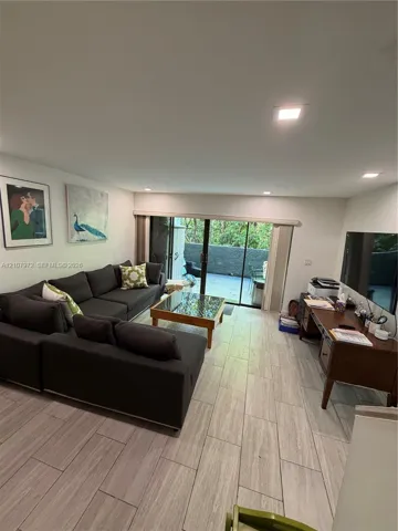 Living space featuring wood-finish tile flooring, recessed lighting, and sliding glass doors with outdoor access