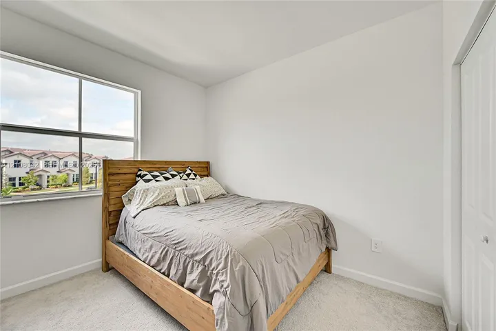 Neutral-toned room featuring wall-to-wall carpeting, a large single-pane window, and a white six-panel closet door