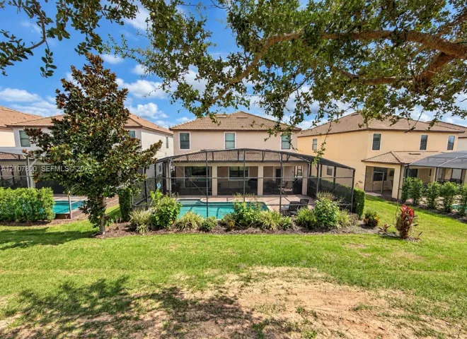Stucco exterior residence featuring a screened-in lanai, private swimming pool, brick paver patio, and landscaped perimeter