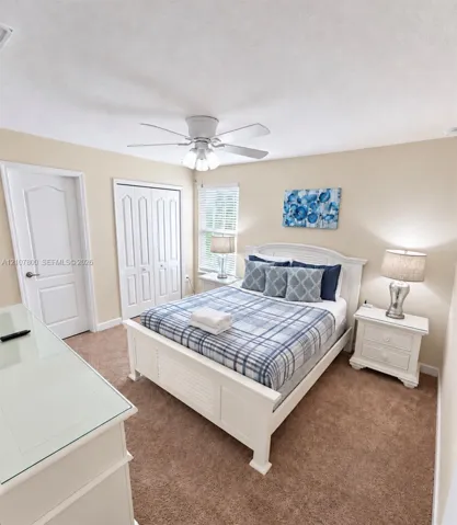 Bedroom featuring neutral carpeting, a ceiling-mounted light fixture with a central fan, and a built-in closet with double doors