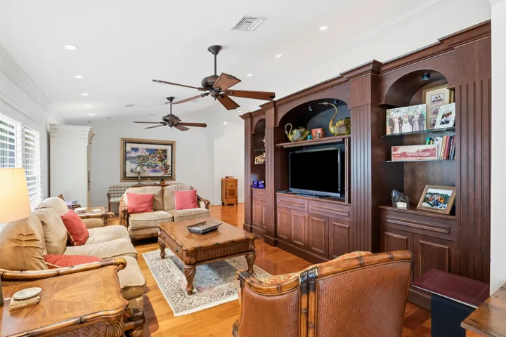 Custom wood-finish built-in cabinetry featuring arched display niches and integrated shelving, hardwood flooring, recessed ceiling lighting, and dual ceiling fans
