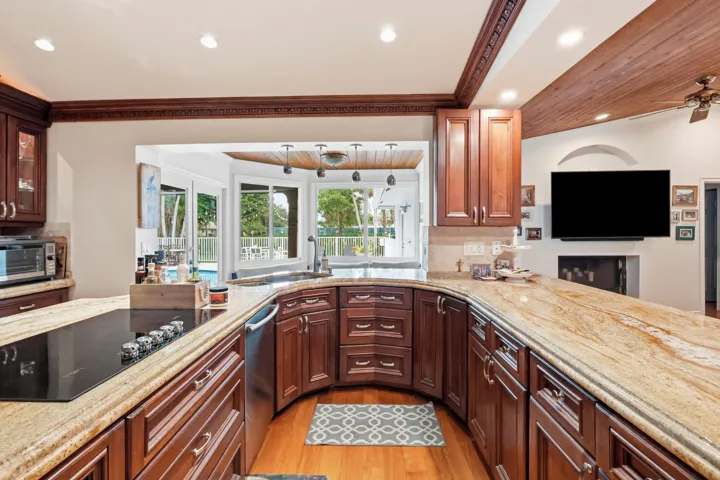 Kitchen featuring wood cabinetry, stone countertops, an integrated cooktop, recessed lighting, and a wood-paneled ceiling accent