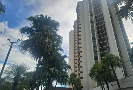 High-rise residential building featuring a concrete facade, curved architectural elements, and private tiered balconies