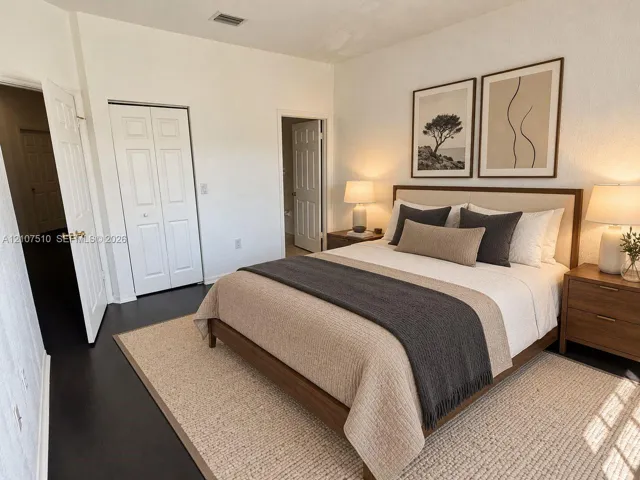 Room featuring dark wood-finish flooring, white walls, and a bi-fold closet door
