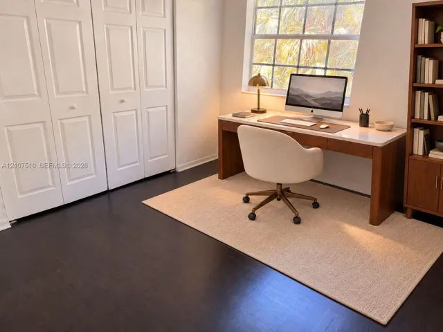 Room featuring dark wood-finish flooring, white panel-style closet doors, and a multi-pane window