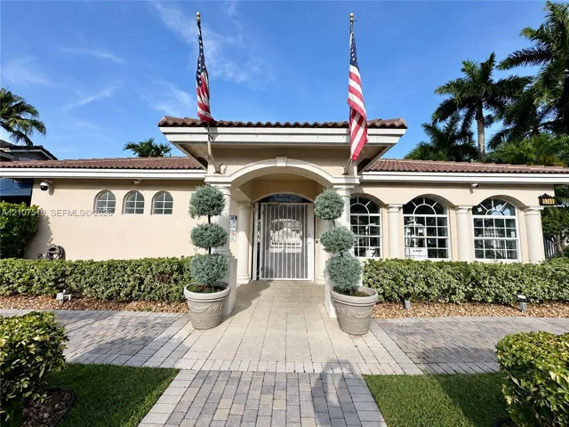 Stucco exterior featuring a covered entryway with arched openings, classic columns, tile roof, and a paver stone walkway