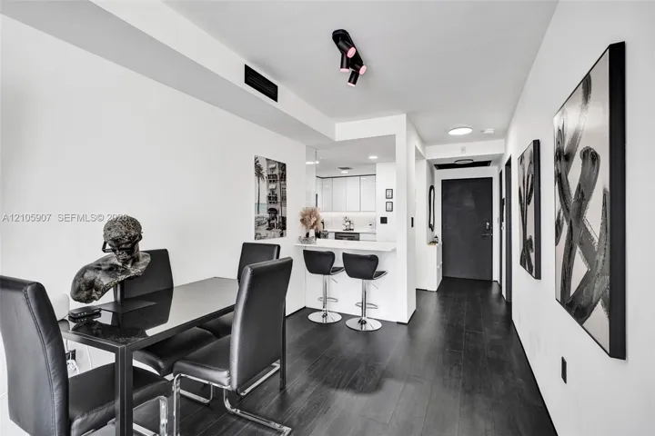 Open-concept interior featuring dark wood-finish flooring, matte black track lighting, and a breakfast bar with stone-finish countertops