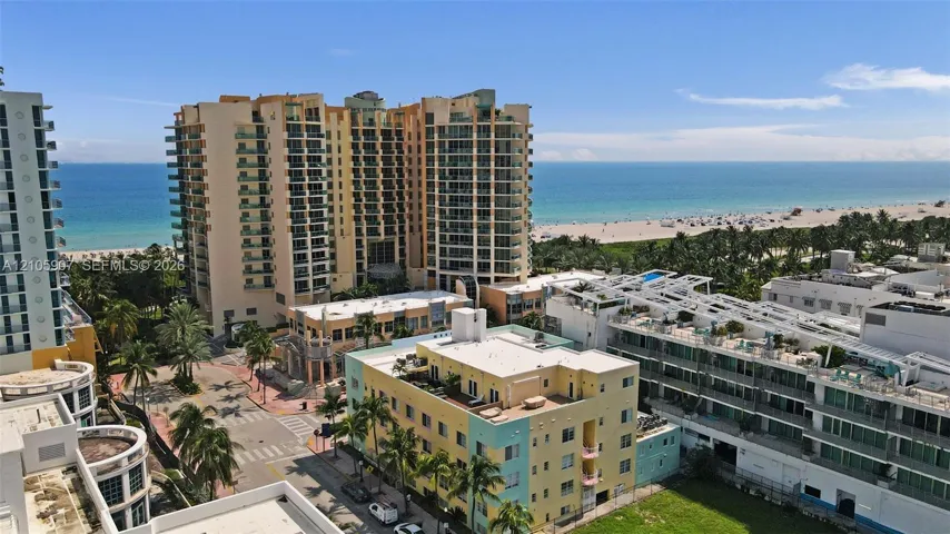 High-rise coastal residential structures featuring expansive glass balcony railings, prominent oceanfront proximity, and established tropical landscaping
