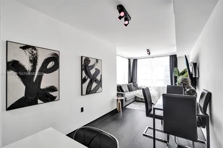 Dark wood-finish flooring, white walls, and multiple adjustable multi-directional track lighting fixtures