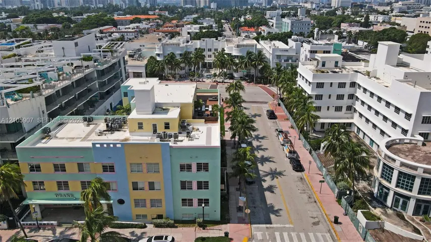Aerial perspective of a multi-story, pastel-colored masonry building featuring a flat roof and ground-level storefront