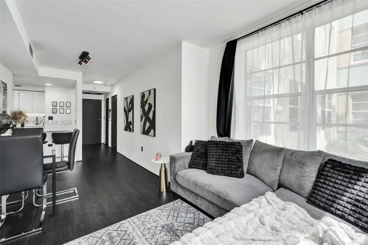 Living area featuring wood-finish flooring, large multi-pane windows, recessed ceiling lighting, and a neutral color palette