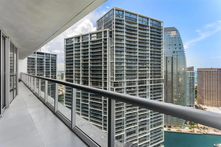 Private balcony featuring large-format tile flooring, a glass-panel railing, and a metal handrail