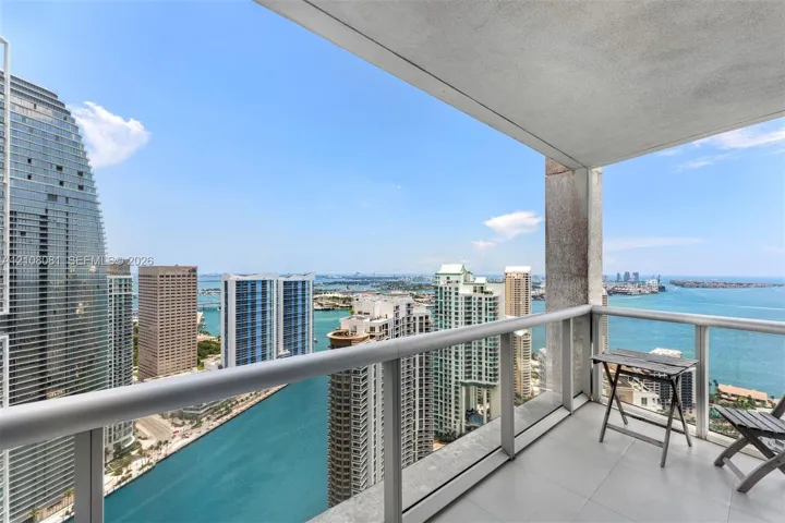 Covered private balcony featuring tile flooring and a glass railing