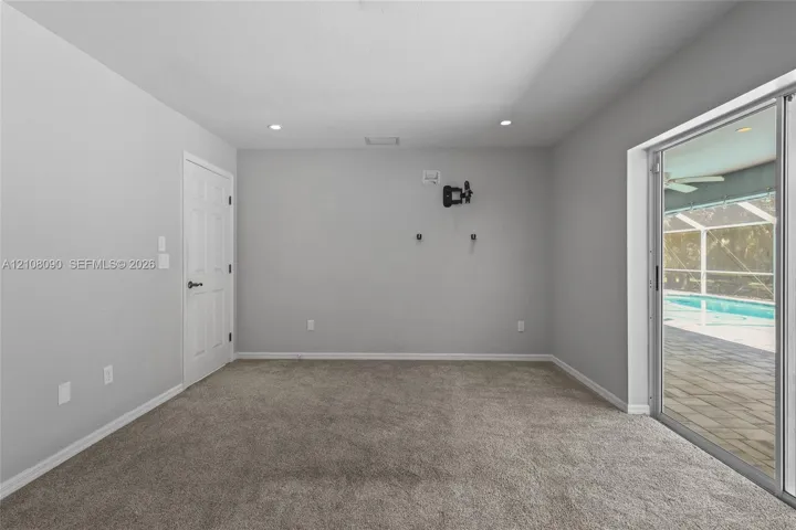 Interior space featuring neutral wall tones, recessed lighting, carpeted flooring, and a sliding glass door providing external access