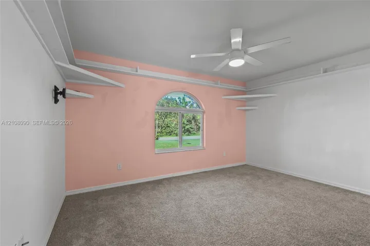 Arched window, ceiling fan with integrated lighting, and built-in tiered wall shelving