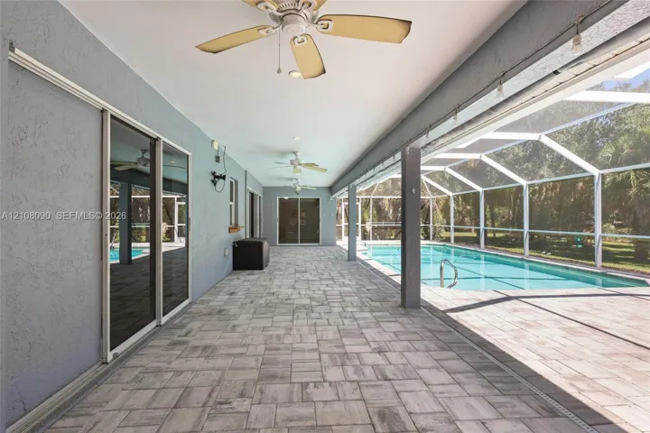 Covered lanai featuring concrete paver flooring, multiple ceiling fans, recessed lighting, and a screened-in swimming pool
