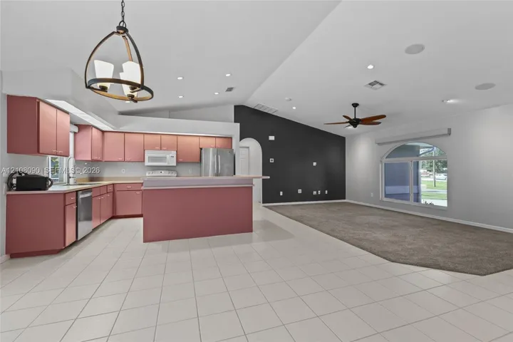 Open-concept kitchen featuring cabinetry, a central island, and recessed lighting, vaulted ceilings, and an arched window