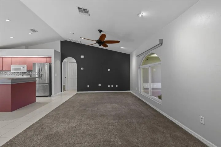 Vaulted ceilings, dark-toned accent wall, arched doorway, recessed lighting, and an arched window