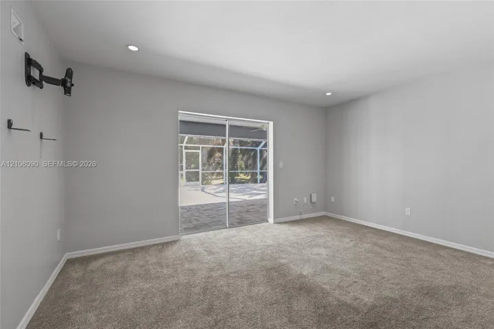 Neutral interior featuring plush wall-to-wall carpeting, recessed lighting, and sliding glass doors leading to a screened outdoor patio