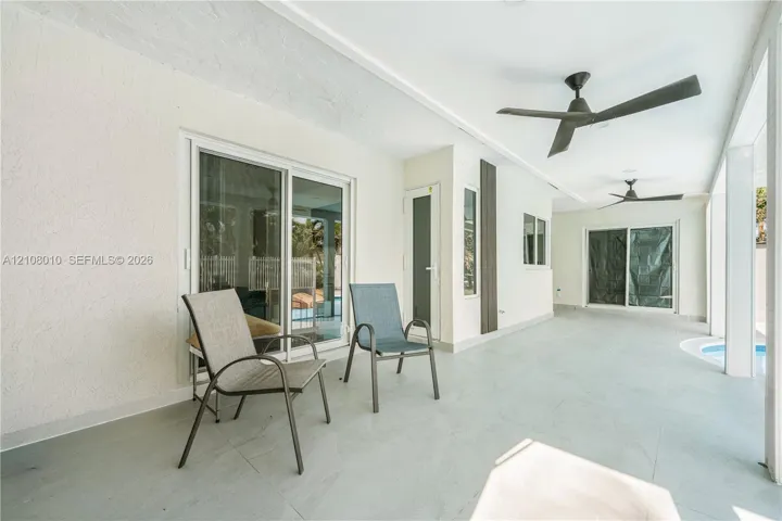 Covered patio featuring concrete flooring, dual ceiling fans, sliding glass doors, and recessed exterior lighting