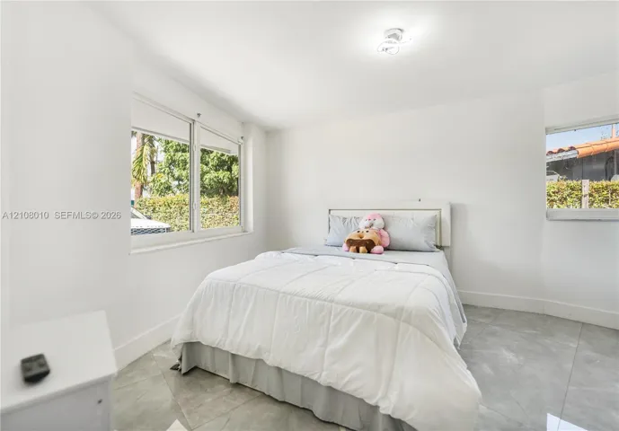 Neutral-toned interior space featuring large-format ceramic tile flooring, bright white wall finishes, sliding windows, and a flush-mount ceiling light fixture
