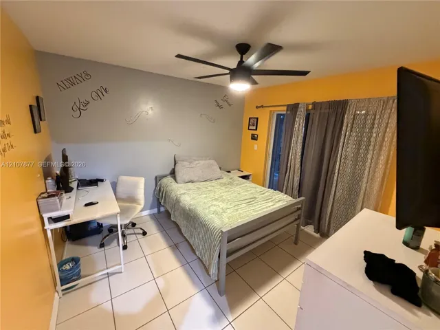 Room featuring neutral floor tiling, a ceiling fan with integrated lighting, and sliding glass patio doors