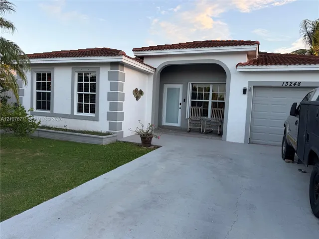 Stucco exterior featuring quoin detailing, clay tile roofing, arched entryway, and a concrete driveway