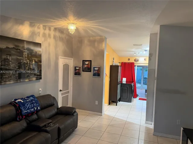 Interior space featuring light-toned ceramic tile flooring, vaulted ceilings, a crystal-style flush-mount light fixture, and an arched-panel interior door