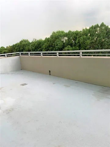 Outdoor terrace featuring a solid parapet wall, metal railing, and surface-level drainage