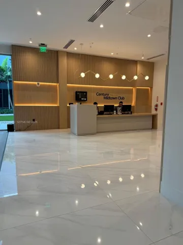 Reception area featuring polished tile flooring, fluted wood wall paneling, integrated recessed accent lighting, and a linear pendant light fixture