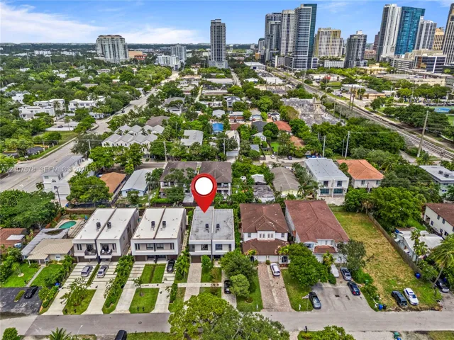 Aerial perspective showcasing a multi-level residential structure with a flat roof, integrated garage, concrete-paved driveway, and proximity to high-rise metropolitan infrastructure