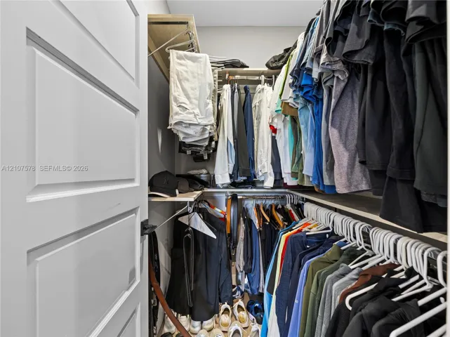 Reach-in closet featuring multi-level wood-finish shelving and integrated hanging rods