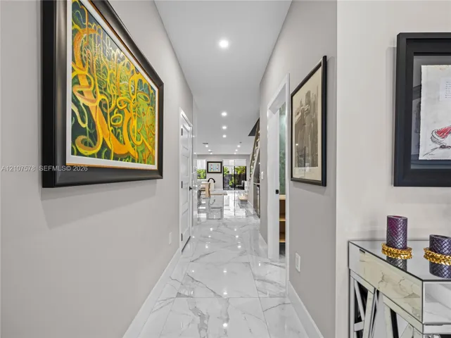 Neutral-toned interior hallway featuring large-format stone-finish tile flooring, recessed ceiling lighting, and multi-panel interior doors