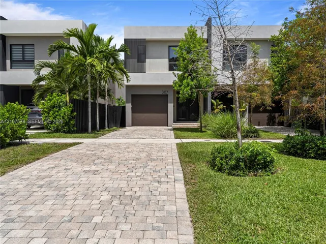 Contemporary two-story exterior featuring a smooth stucco facade, paver driveway, and an integrated single-car garage