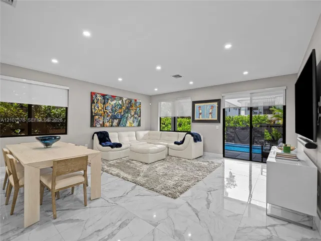 Open-concept living space featuring high-gloss large-format floor tiling, recessed lighting, and sliding glass doors with exterior patio and pool access