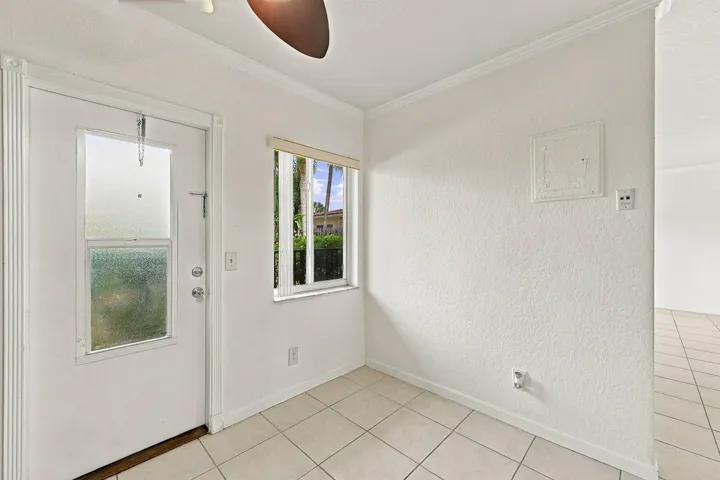 Entryway featuring neutral tile flooring, textured wall finishes, crown molding, and a door with an integrated window panel