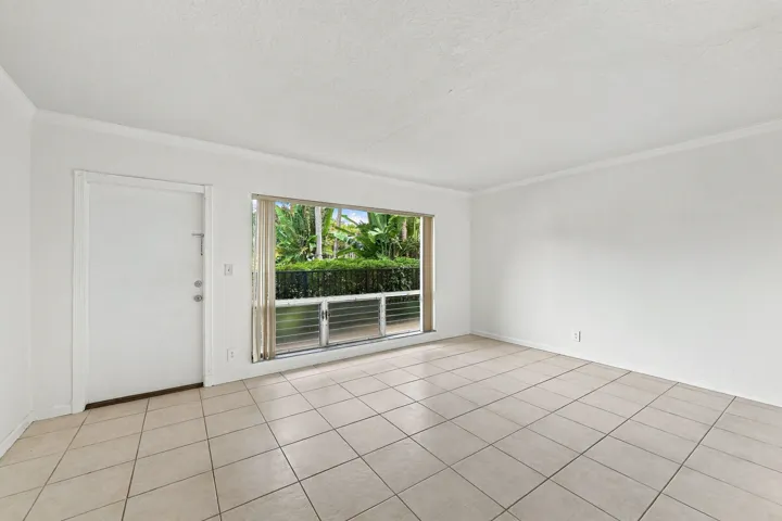 Neutral-toned ceramic tile flooring, large picture window with horizontal mullions, solid-core entry door, and crisp white wall finishes