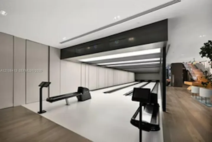Multi-lane bowling alley featuring recessed ceiling lighting, wood-finish flooring, paneled wall detailing, and integrated console displays